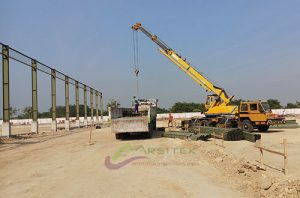 Alat berat mobil crane sedang bongkar material baja