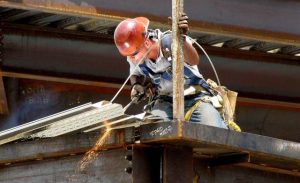 Pekerja konstruksi yang sedang melaksanakan pekerjaan bongkar pasang material baja